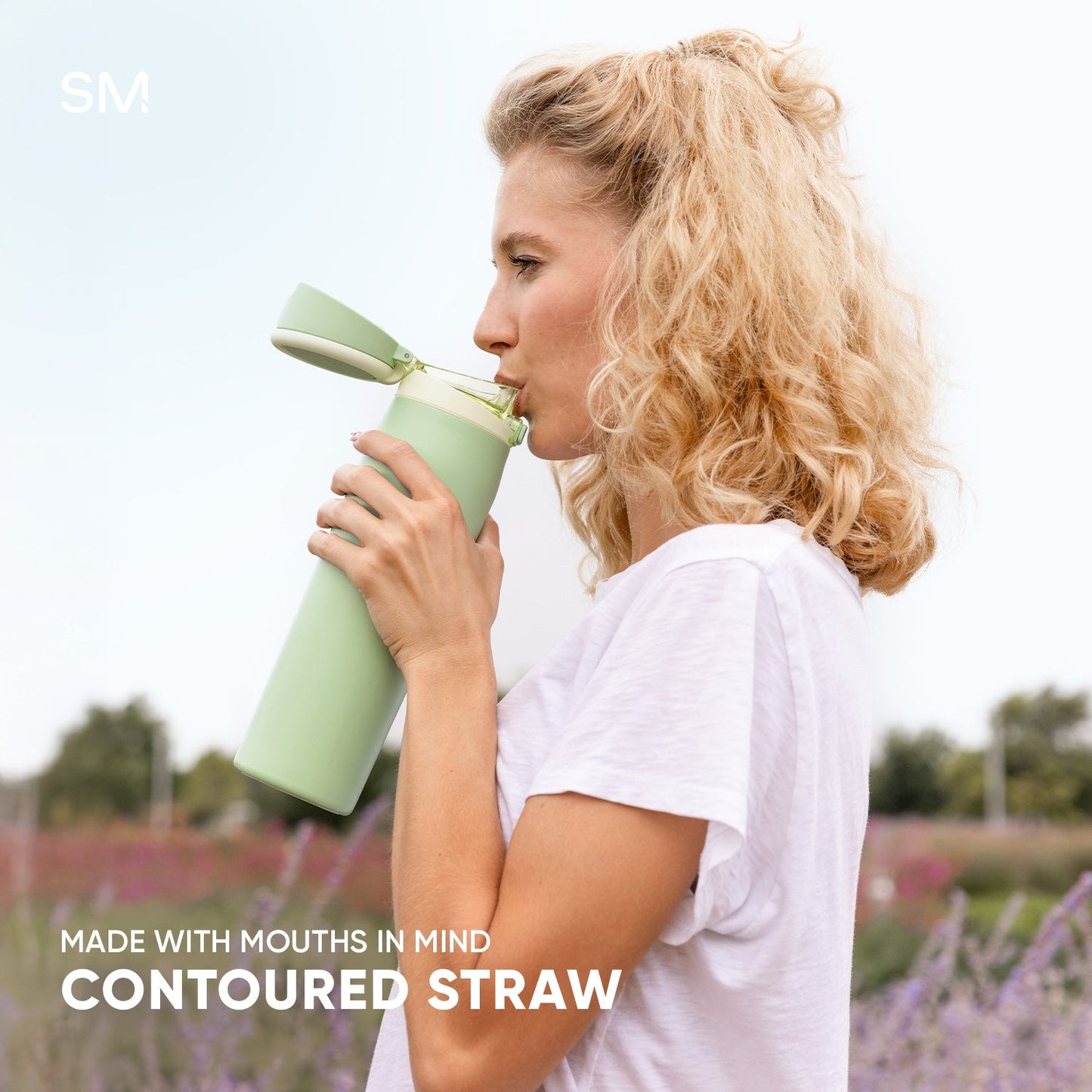 Woman with blonde hair drinking from a pale sage green contoured water bottle with matching straw in a lavender field. Text reads "Made with Mouths in Mind" and "Contoured Straw."