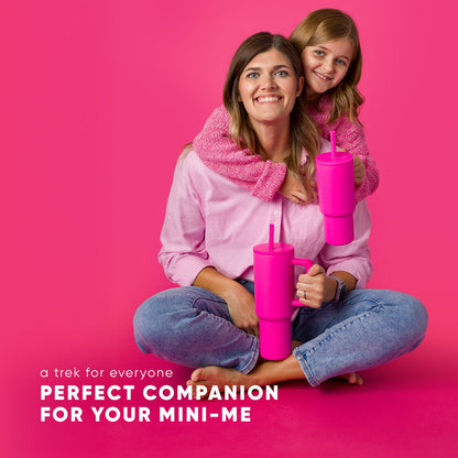Adult woman and child smiling together against hot pink background, both holding matching Simple Modern 24oz hot pink Trek tumblers with straws. Both wear blue jeans and pink scarves. Text reads "Perfect companion for your