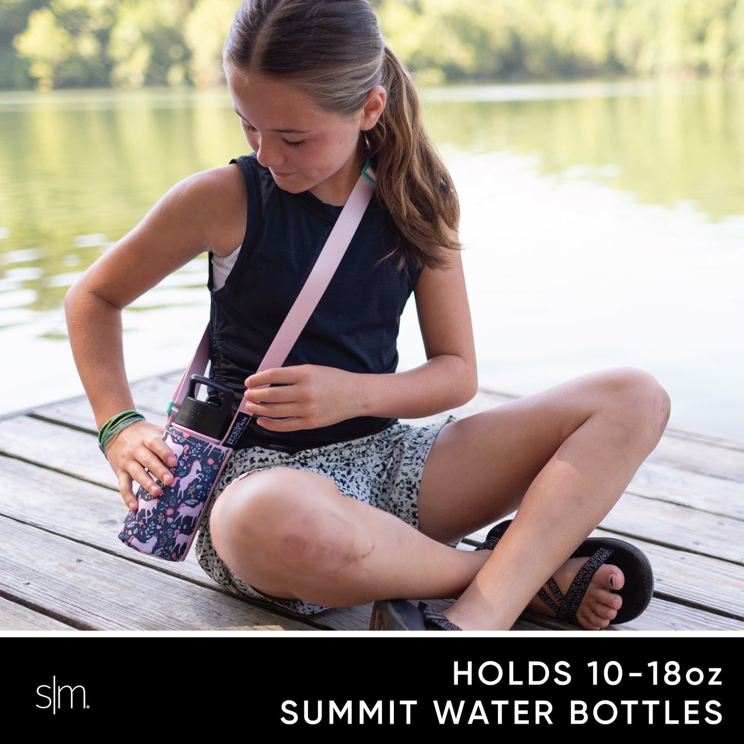Child wearing pale pink adjustable sling carrier with water bottle holder across chest, paired with black sleeveless top, demonstrating hands-free carrying solution for kids' adventures.