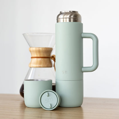 Sage green insulated tumbler with handle, matching cup, and circular lid on a neutral background